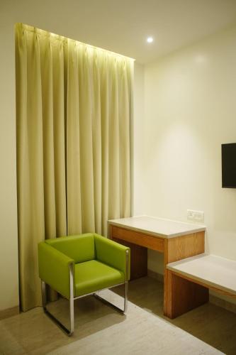 a green chair in a room with a desk at Hotel Rancehok's Mathura in Gokul