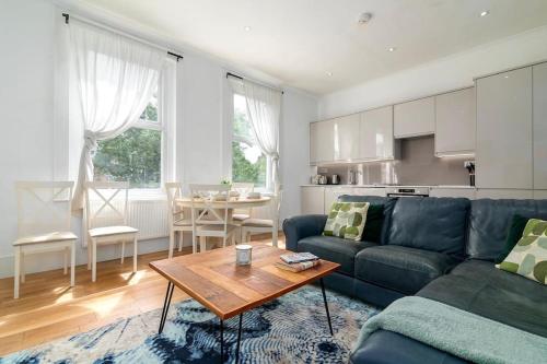 a living room with a blue couch and a table at Modern Spacious 2 Bedroom Flat near Richmond Park in London
