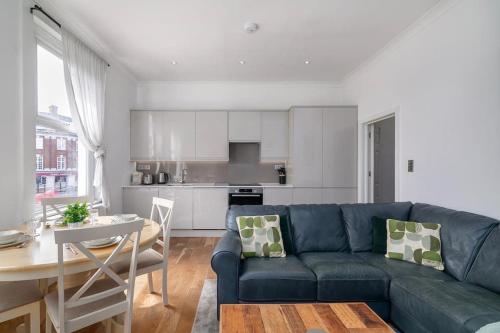 a living room with a blue couch and a kitchen at Modern Spacious 2 Bedroom Flat near Richmond Park in London