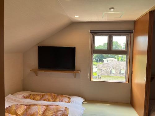 a bedroom with a flat screen tv and a bed at Royal Hotel Kawaguchiko in Fujikawaguchiko