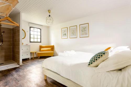 a bedroom with a white bed and a yellow chair at Domaine de Bouhémy in Solférino