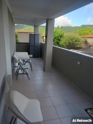 a balcony with chairs and a table and a view at Maison charmante à Rivière-Pilote avec vue sur la montagne in Rivière-Pilote