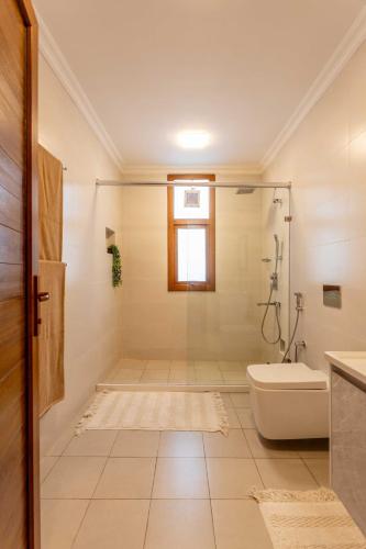 a white bathroom with a shower and a toilet at Villa Serene in Bwejuu