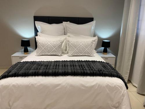 a bedroom with a large bed with black and white pillows at The Manor in Midrand