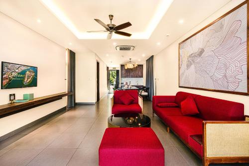 a living room with red furniture and a ceiling fan at Hoi An Memories Resort & Spa in Hoi An