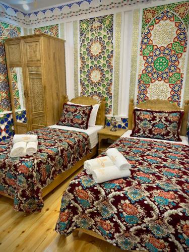 a bedroom with two beds and colorful wallpaper at MERITON Boutique in Bukhara
