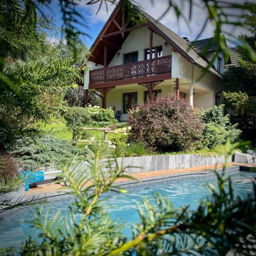 a house with a swimming pool in front of it at Apartamenty Kornaje - Szczawnica Jaworki - komfortowe apartamenty, basen, sauna, duży ogród, blisko szlaków i stoku narciarskiego in Szczawnica