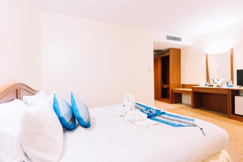 a bedroom with a white bed with blue pillows at Chumphon Gardens Hotel in Chumphon