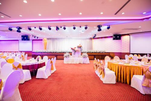 a banquet hall with white tables and white chairs at Chumphon Gardens Hotel in Chumphon