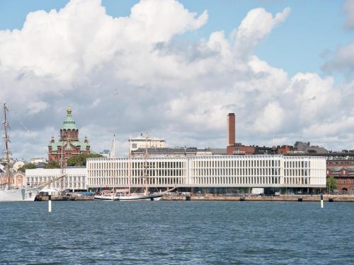 a white building on the water in front of a city at Solo Sokos Hotel Pier 4 in Helsinki