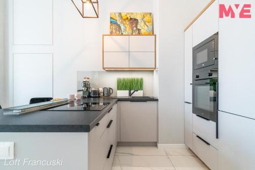 a kitchen with white cabinets and a black counter top at MYE Apartments - Kamienica Sienkiewicza in Łódź