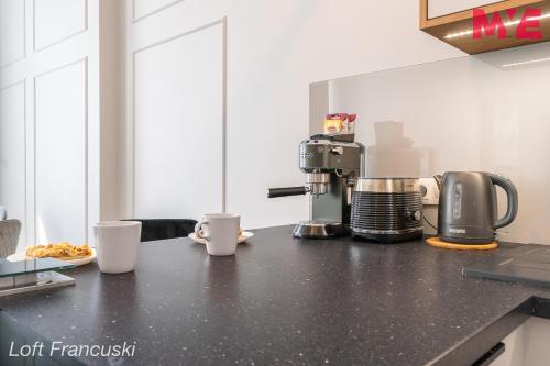 a kitchen counter with a coffee maker and cups on it at MYE Apartments - Kamienica Sienkiewicza in Łódź