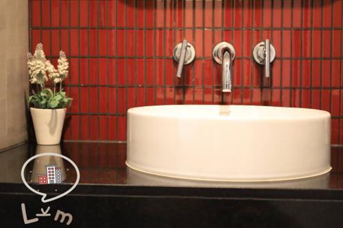 a white sink in a bathroom with a red wall at The Central Pattaya High Floor, Pattaya City in Pattaya Central