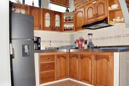 a kitchen with wooden cabinets and a refrigerator at Lago Calima Cozy Cabin in Calima