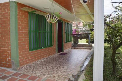 a brick house with green windows and a porch at Lago Calima Cozy Cabin in Calima