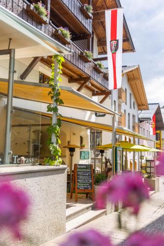 a restaurant with purple flowers in front of a building at Hotel zum Hirschen Zell am See in Zell am See