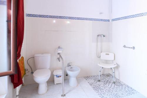 a white bathroom with a toilet and a sink at Molino Los Cardenes 1911 in Montoro
