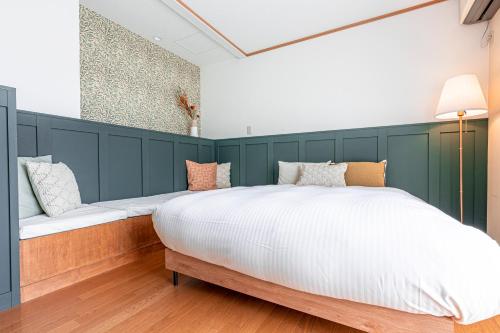 a bedroom with a large white bed with a green wall at ガーデンテラス伊豆高原 in Futo