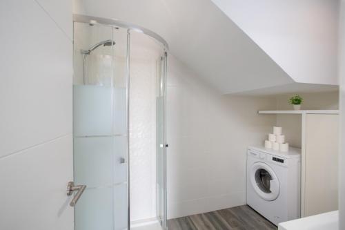 a white bathroom with a shower and a washing machine at Casa Judit in Los Silos