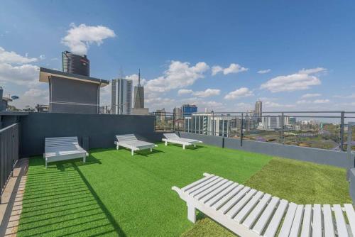 three white benches sitting on top of a roof at Lovely Condomnium on 10th floor in Nairobi