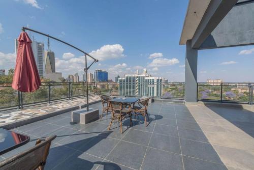 a patio with a table and chairs on a roof at Lovely Condomnium on 10th floor in Nairobi