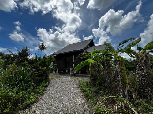 a house with a black roof on a gravel road at LOG AMAMl 1棟貸切ログハウス in Setouchi