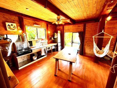 a living room with a table and a hammock in a cabin at LOG AMAMl 1棟貸切ログハウス in Setouchi