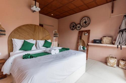 a bedroom with a large white bed with green pillows at Woywoy Escape Tabo - Adults Only in Ubud