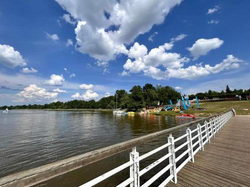 a wooden boardwalk next to a lake with boats on it at Apartament u Ani in Iława