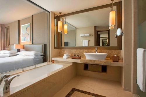 a bathroom with a tub and a bed and a sink at Sheraton Bailuhu Resort, Huizhou in Huizhou