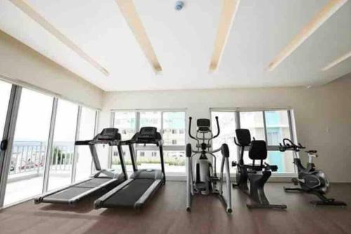 a gym with treadmills and exercise bikes in a room with windows at DaLei 1-319 Sleeps 8pax at Marina Spatial Condominium in Dumaguete City in Dumaguete