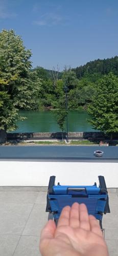a hand holding a blue object in front of a view at Apartman Una na dlanu, Novi Grad in Bosanski Novi