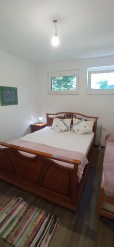 a bedroom with a large wooden bed with two windows at Apartman Una na dlanu, Novi Grad in Bosanski Novi