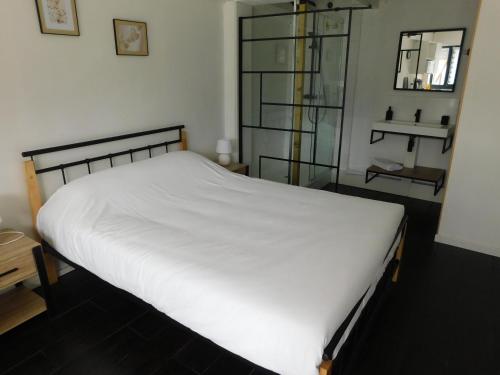 a bedroom with a white bed and a glass shelf at Tsara Home in Le Trait