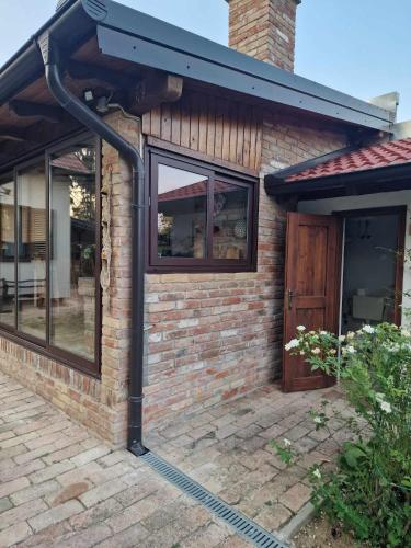 a brick house with a black roof and a door at Kuća za odmor Mali Princ in Karanac