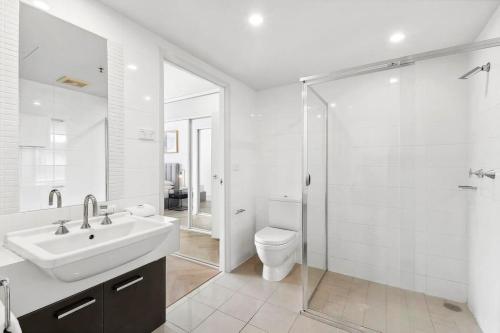 a bathroom with a sink and a toilet and a shower at Modern Renovated CBD Apartment in Canberra