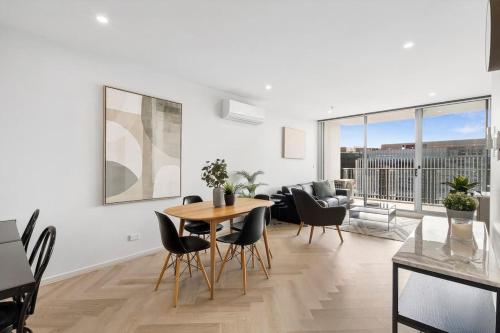 a white living room with a table and chairs at Modern Renovated CBD Apartment in Canberra
