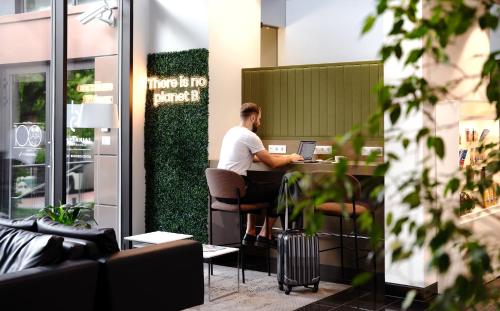 a man sitting at a table with a laptop at Centennial Nexus Hotel Tallinn in Tallinn