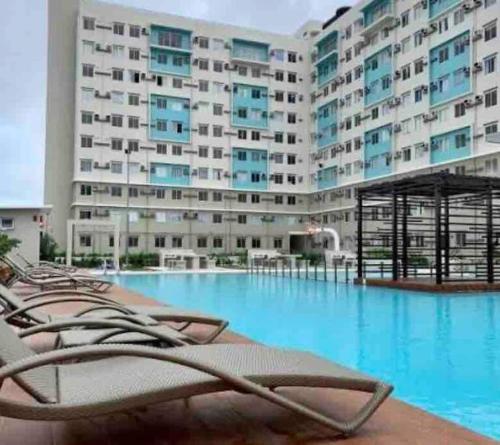 a hotel swimming pool with lounge chairs in front of a building at DaLei 2-330 Sleeps 8pax at Marina Spatial Condominium in Dumaguete City in Dumaguete
