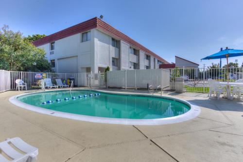 a swimming pool with chairs and a building at Motel 6-Portland, OR - Tigard West in Tigard