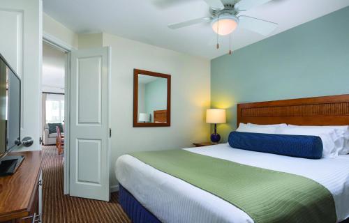 a bedroom with a large bed and a mirror at Club Wyndham Oceanside Pier Resort in Oceanside