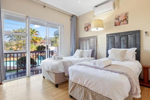 two beds in a bedroom with a balcony at Gainsford Place 26 by Host Agents in Durban