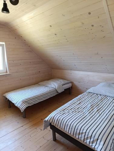 two beds in a room in a wooden cabin at Słoneczne Wzgórze nad Dadajem Domek 1 in Biskupiec