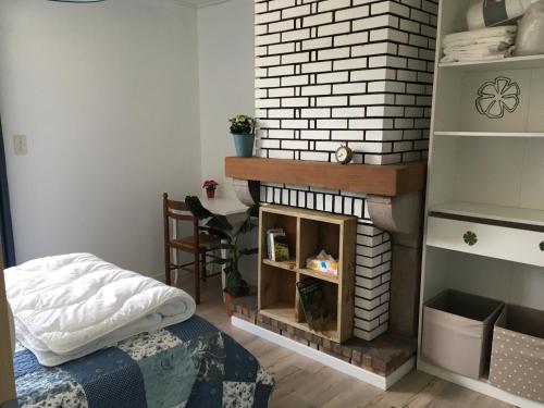 - un salon avec une cheminée en briques et un lit dans l'établissement Chez Loulou chambre indépendante, à Léon