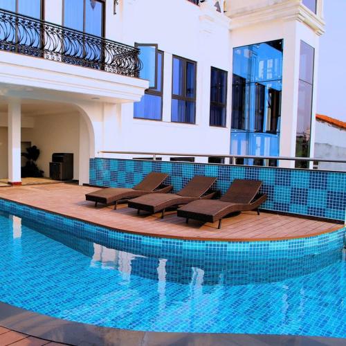a swimming pool with chairs and a house at SALA HOTEL HUE in Hue