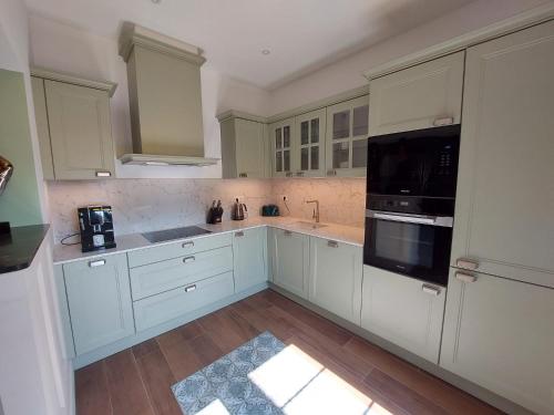 une cuisine avec des armoires blanches et des appareils noirs dans l'établissement Arcachonnaise - centre ville - 500m de la plage, à Arcachon