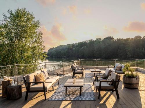 a patio with couches and tables and a view of a lake at Falkensteiner Premium Camping Lake Blagus in Sveti Jurij ob Ščavnici