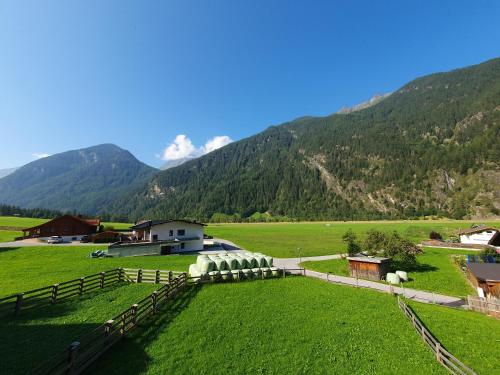 a farm with sheep in a field with mountains in the background at Ferienhaus Gerold Grießer in Umhausen