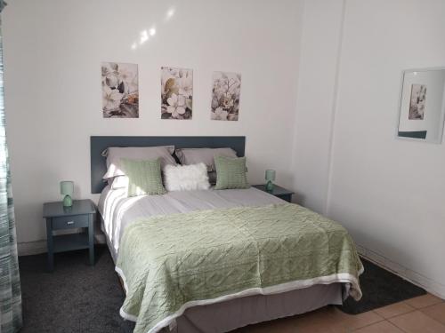 a bedroom with a bed with two tables and two pictures on the wall at The Garden Cottage in Polokwane