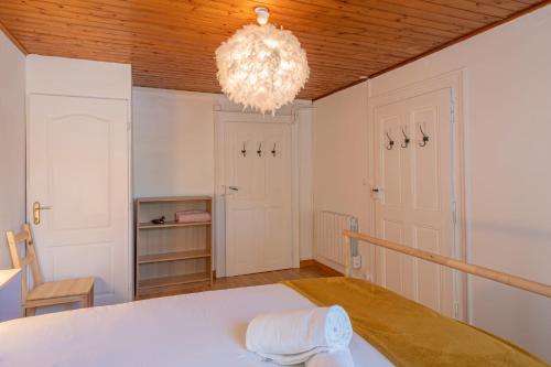 Cette chambre comprend un lit blanc et un lustre. dans l'établissement Rimaye Blanche - A bright and cozy 1 bed apartment, à Chamonix-Mont-Blanc